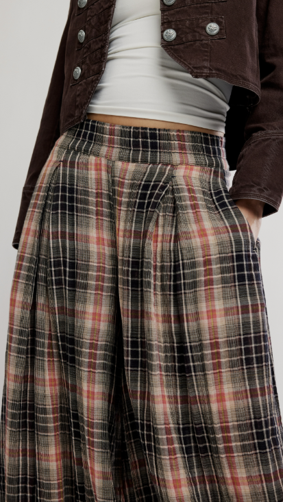 Close up of woman wearing plaid balloon pants with brown jacket on plain background