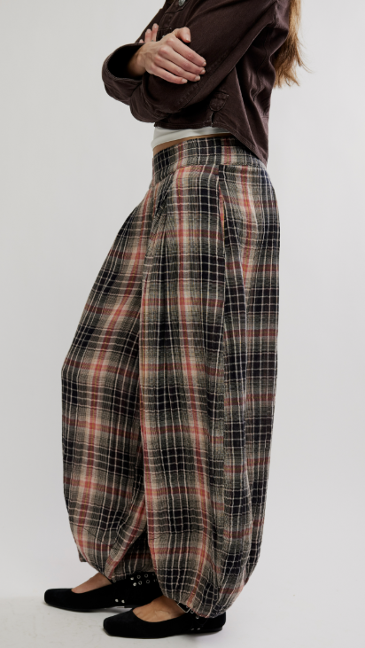 Woman wearing plaid balloon pants with brown jacket on plain background