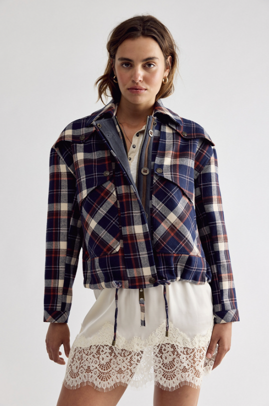Woman wearing navy plaid jacket with white slip skirt on white background