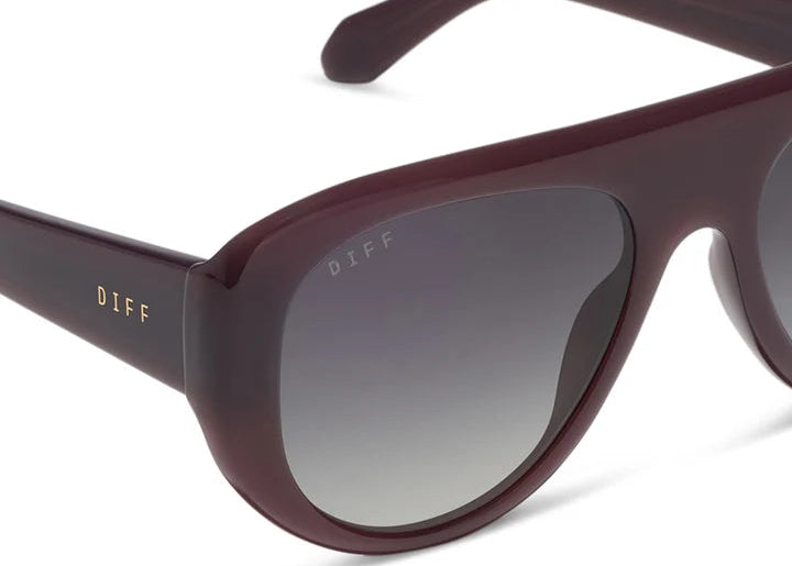 Pair of dark purple sunglasses with grey lenses on white background