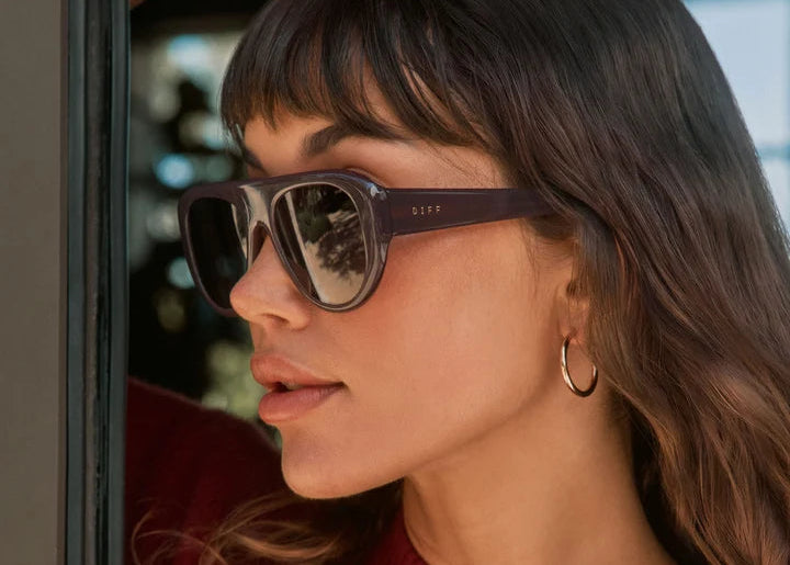 Woman wearing dark purple sunglasses with red shirt standing outdoors
