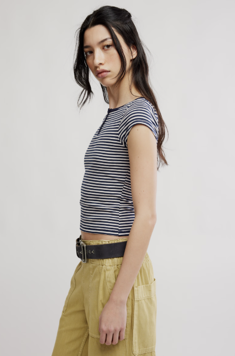 Woman wearing a striped top and yellow pants against a plain background