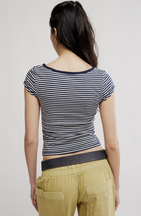 Person wearing a striped shirt and beige pants on a plain background