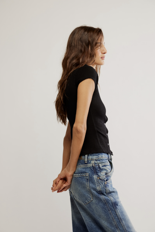 Woman wearing a black top and blue jeans against a plain background