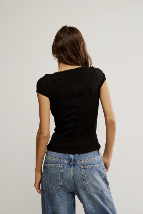 Person wearing a black top and blue jeans on a plain background