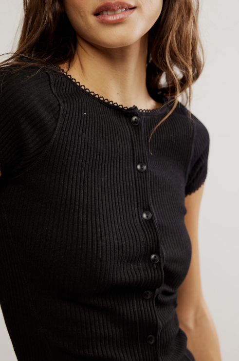 Black ribbed sweater with buttons worn by a person on a plain background