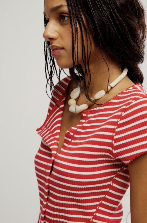 Woman wearing a red and white striped shirt with a necklace against a plain background