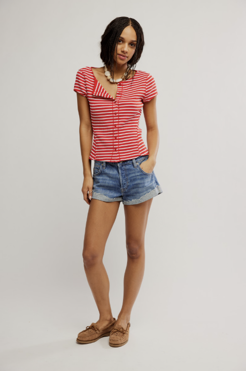 Woman wearing a red and white striped shirt and denim shorts on a plain background
