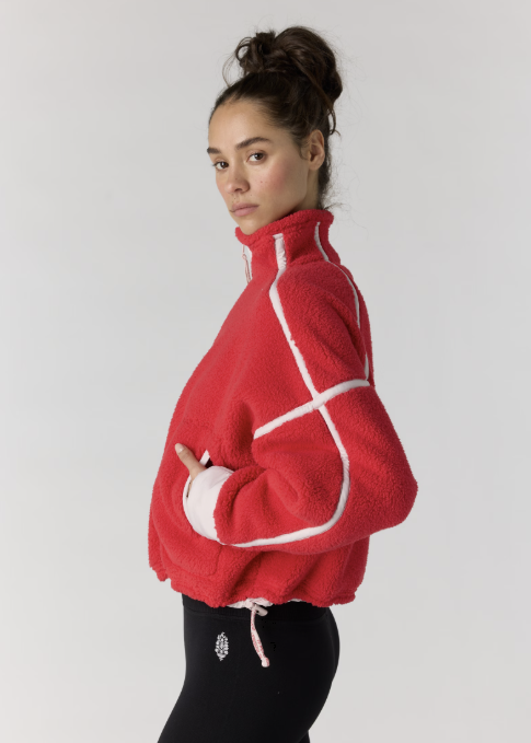 Woman modeling a red fleece pullover with black leggings on plain background