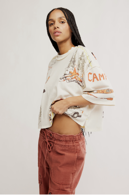 Woman wearing a white oversized sweatshirt with graphics and text, paired with pink pants on a plain background