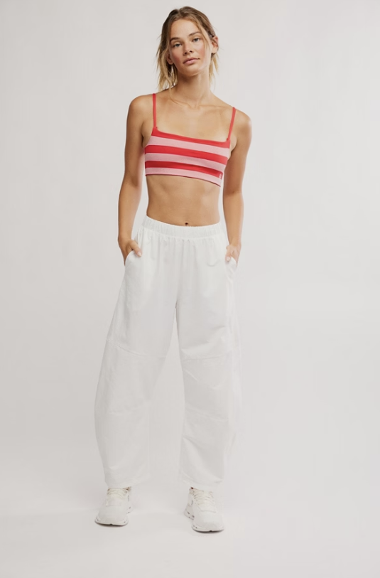 Woman wearing pink and red bra and white pants on white background