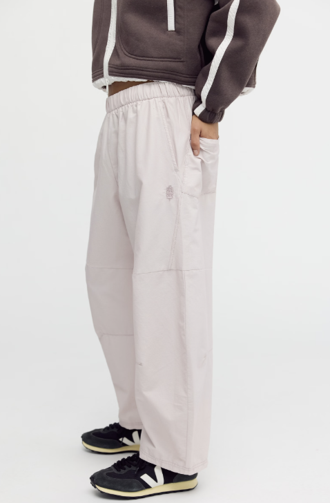 Woman modeling beige pants with brown jacket on white background