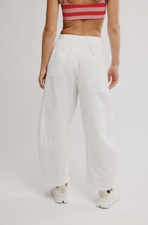 Woman wearing red and pink bra and white pants on white background