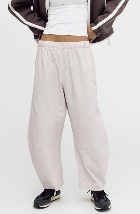 Woman modeling beige pants with brown jacket on white background