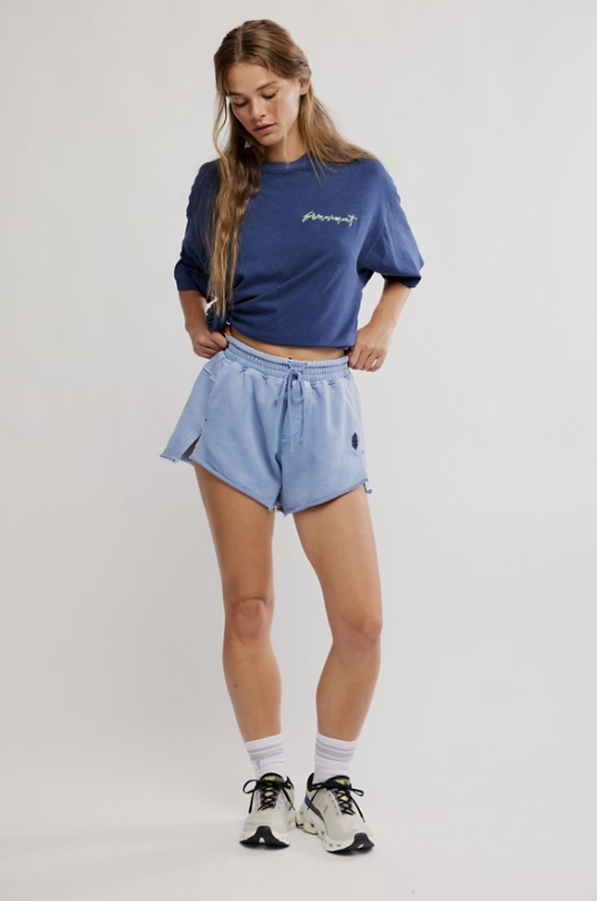 Woman wearing blue tee and shorts on white background