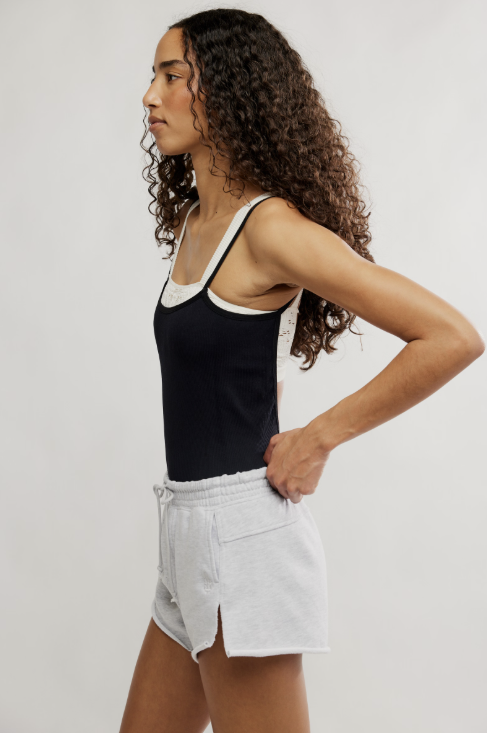 Woman wearing black tank and grey shorts on plain background