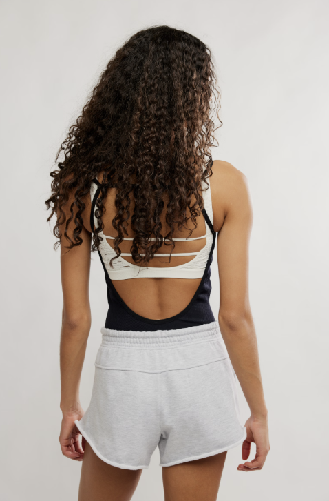 Woman wearing black tank and grey shorts on plain background