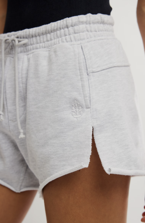 Woman wearing grey shorts on plain background