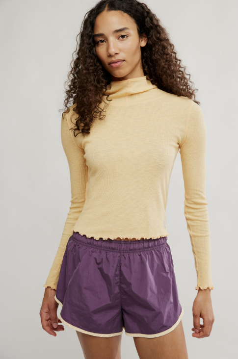 Woman wearing purple shorts and yellow top on white background