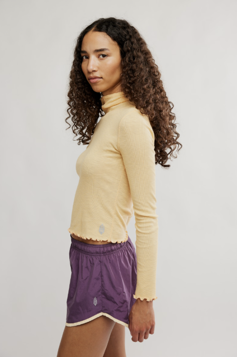 Woman wearing purple shorts and yellow top on white background