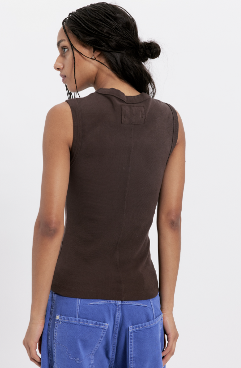 Person wearing a brown sleeveless top and blue pants on a white background