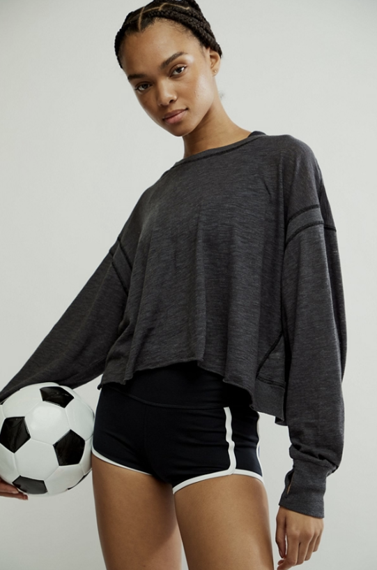 woman wearing black long sleeve holding soccer ball on white background