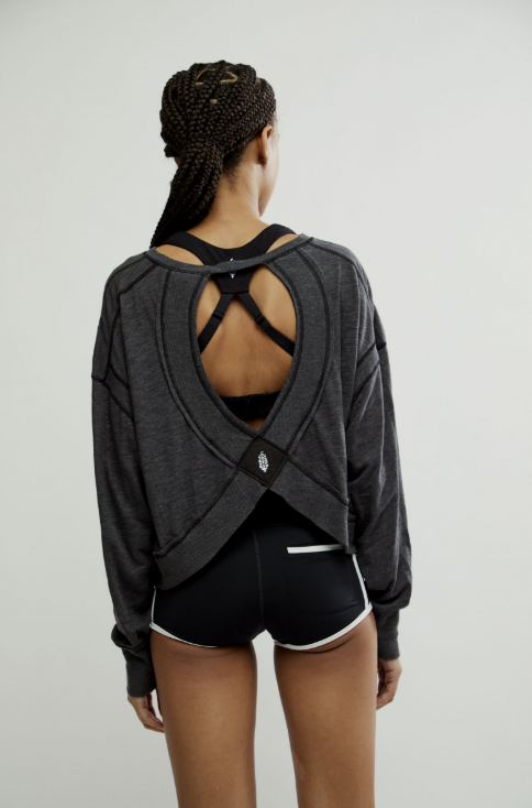 Person wearing a gray open-back top and black shorts on a light gray background