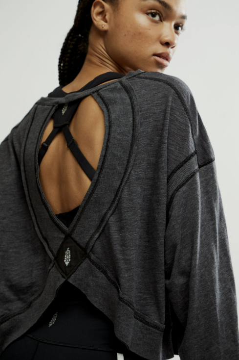 Person wearing a gray open-back top on a plain background