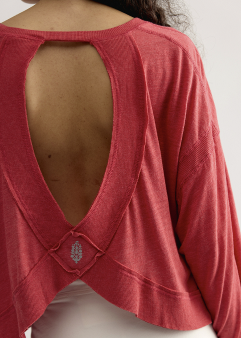 Woman shown from back wearing red long sleeve top with open back detail and white skirt on plain background