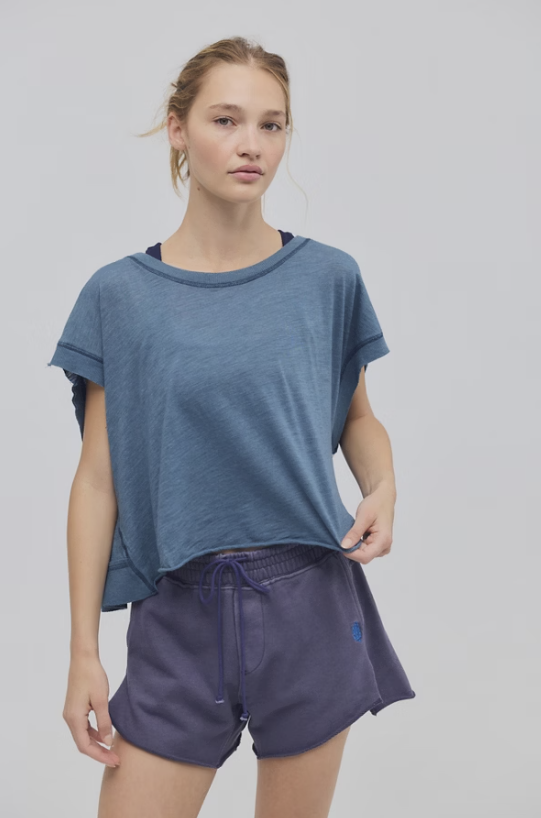 Woman wearing a blue t-shirt and shorts on a plain background
