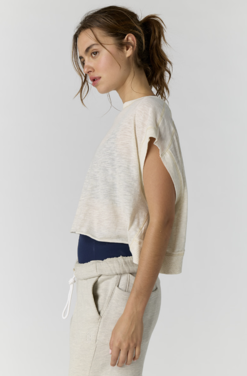 Woman wearing a light-colored top and beige pants against a white background