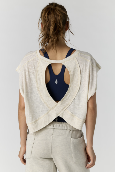 Person wearing a navy tank top and beige cardigan with open back on a white background