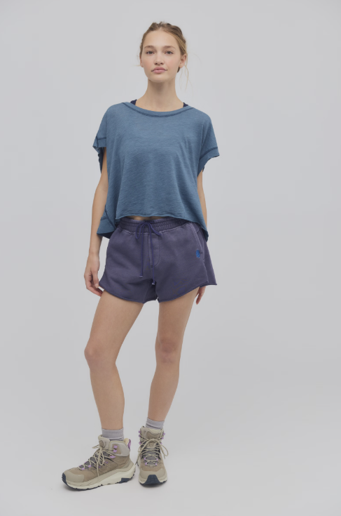 Person wearing a blue t-shirt and purple shorts on a white background