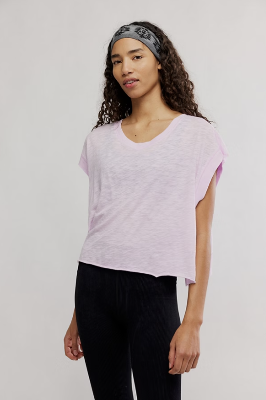 Woman wearing a light purple shirt and black pants on a plain background