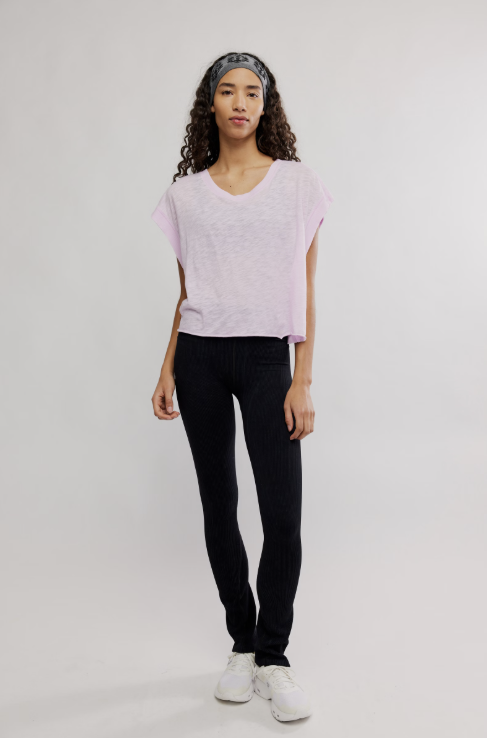Woman wearing a light pink sweater and black pants on a white background