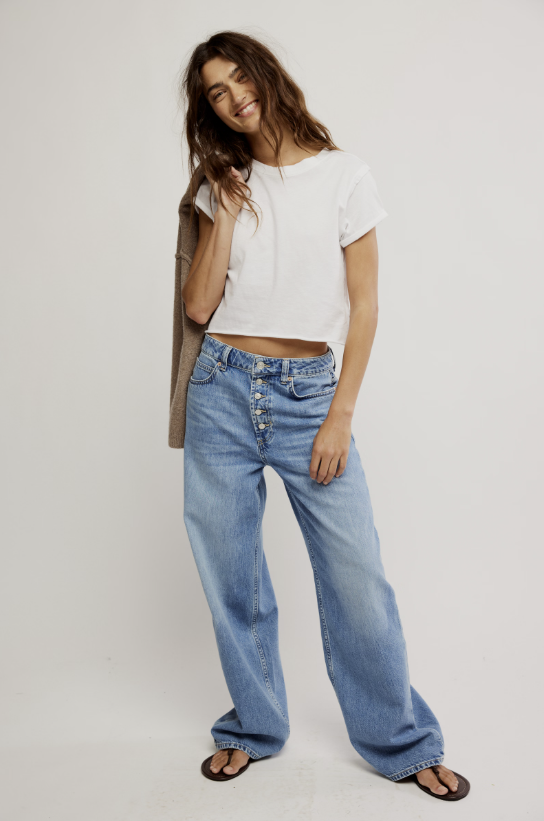 Woman wearing a white top and blue jeans on a plain background