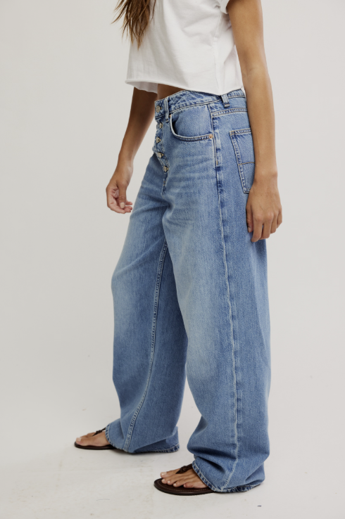 Person wearing light blue jeans on a plain background