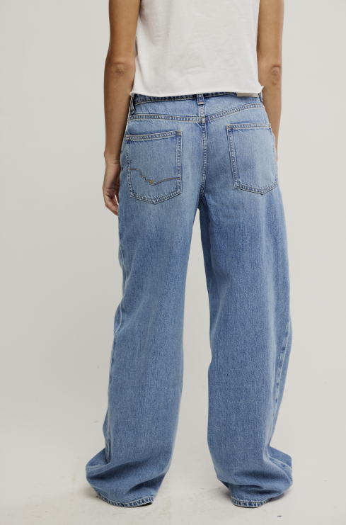 Person wearing light blue jeans on a plain background