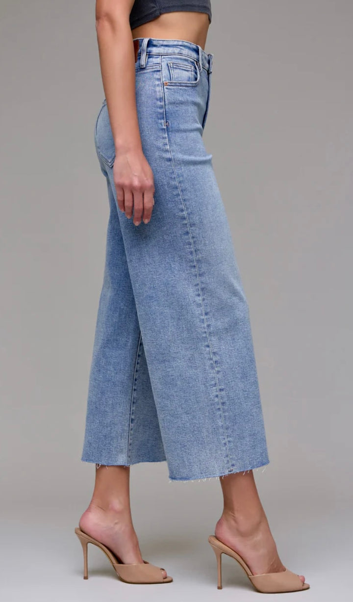 Light blue denim culottes worn by a person on a gray background