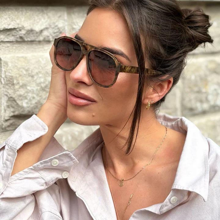 Woman wearing sunglasses with a stone wall background