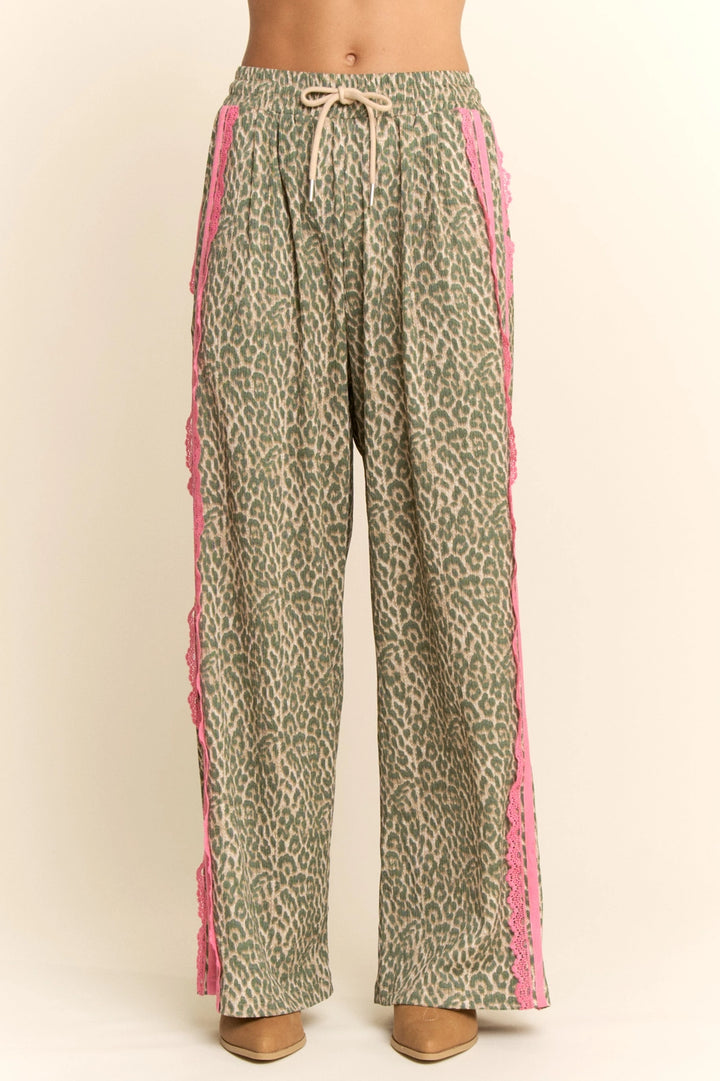 Leopard print pants with pink trim on a beige background