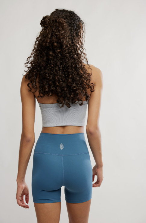 Person wearing a gray sports bra and blue shorts on a plain background