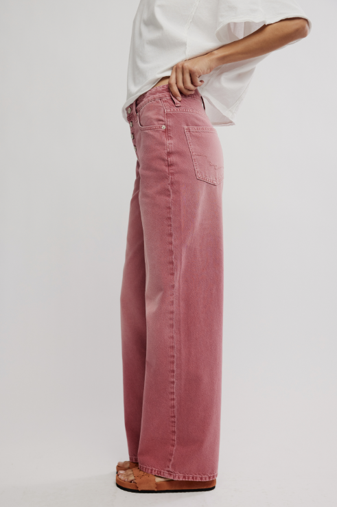 Person wearing pink wide-leg jeans and a white shirt on a light gray background