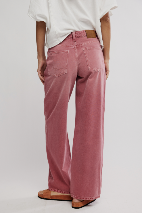 Person wearing pink pants and a white top on a plain background