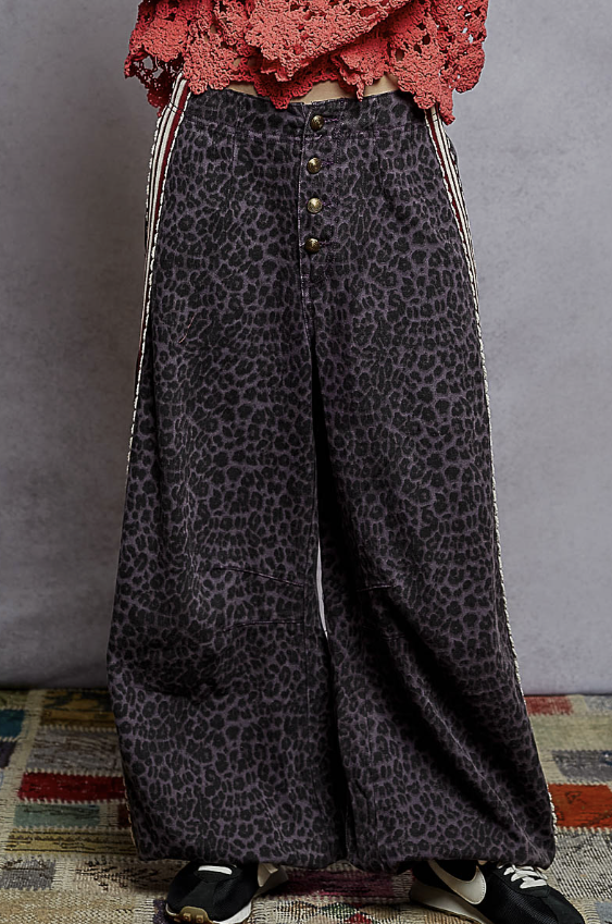 Person wearing leopard print pants with a red top against a gray background