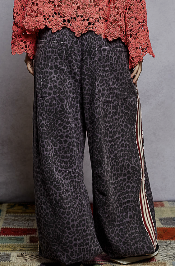Person wearing leopard print pants with a red lace top against a gray background