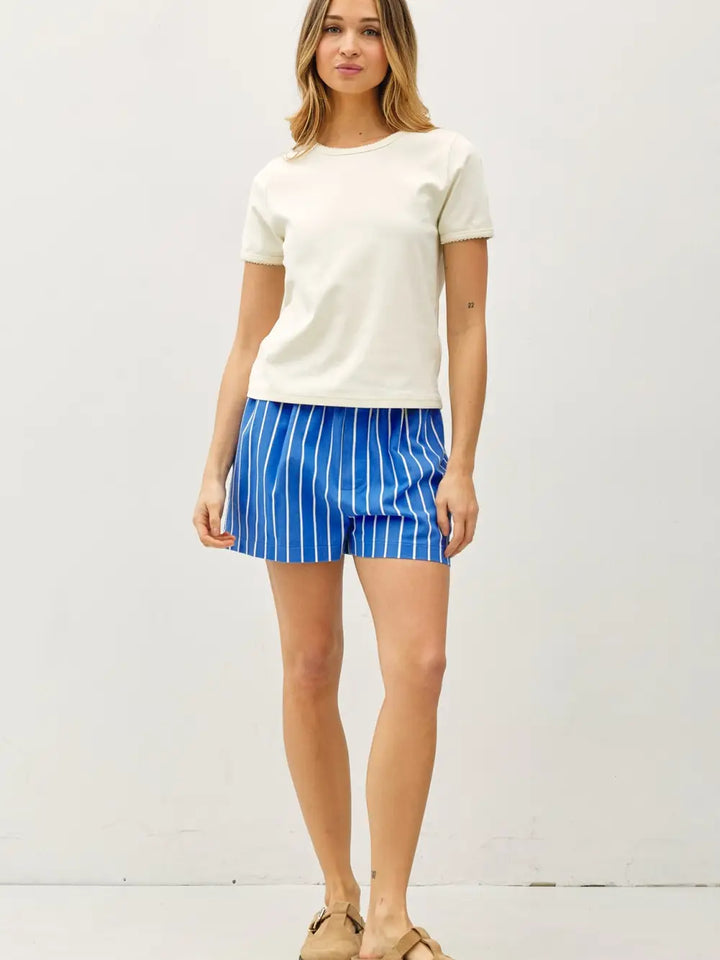 Woman wearing a white t-shirt and blue striped shorts on a white background