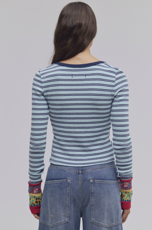 Woman shown from behind wearing blue stripe cardigan and jeans on white background