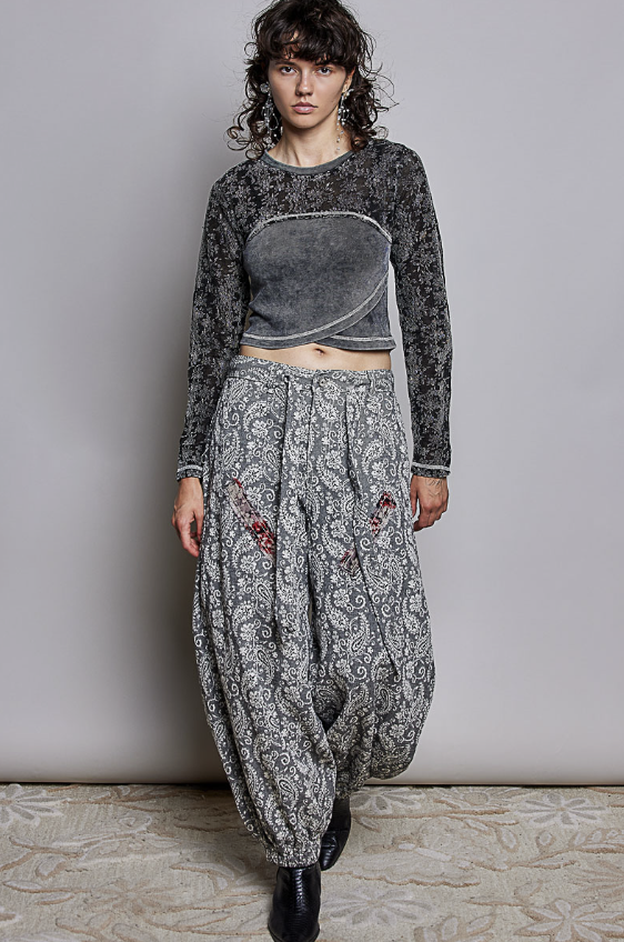 Woman wearing black paisley pants and black shirt on plain background