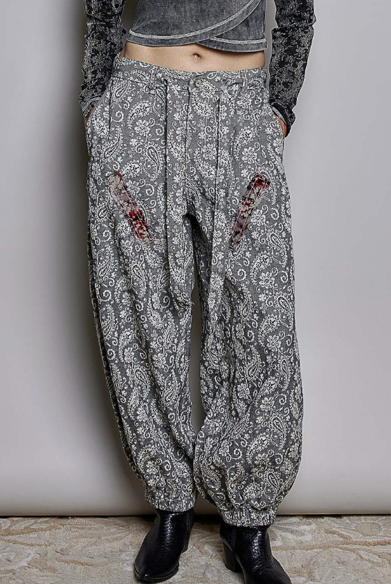 Woman wearing black paisley pants on plain background